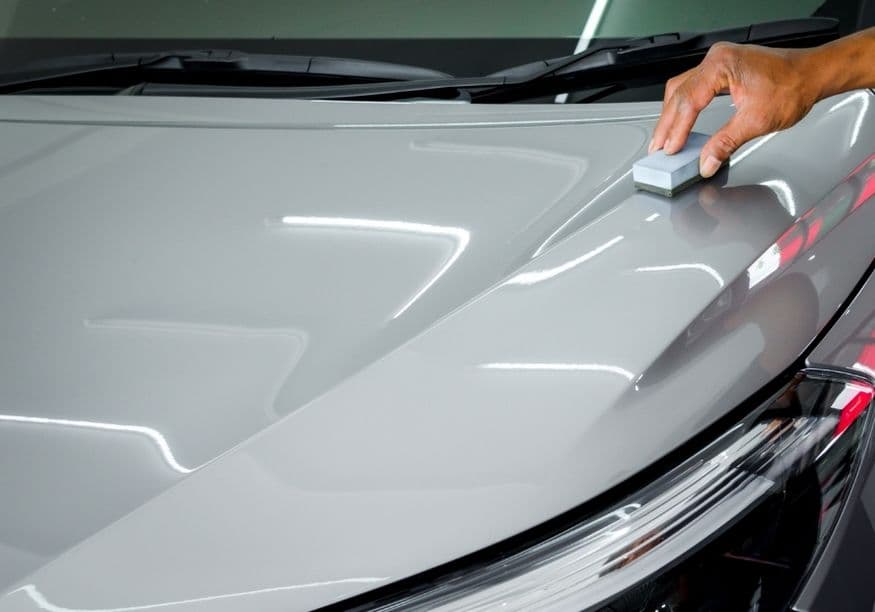 Applying paint protection with an applicator pad on a glossy hood, wax vs sealant application in Vancouver